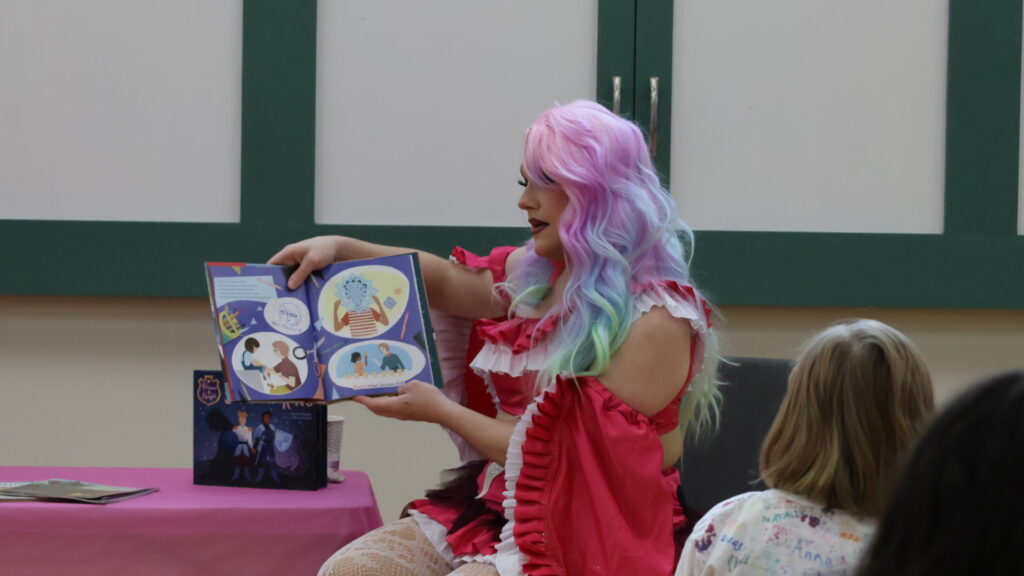 Photo of drag queen Angelica Lize reading from a children's book.