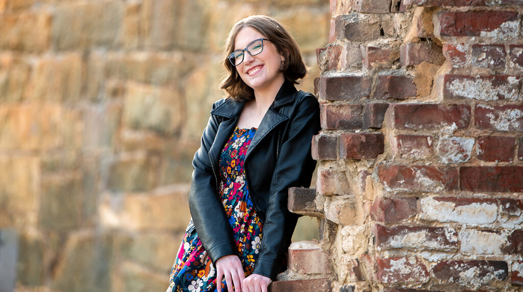 Photo of Girl Scout Kate Lindley leaning against a brick wall and smiling