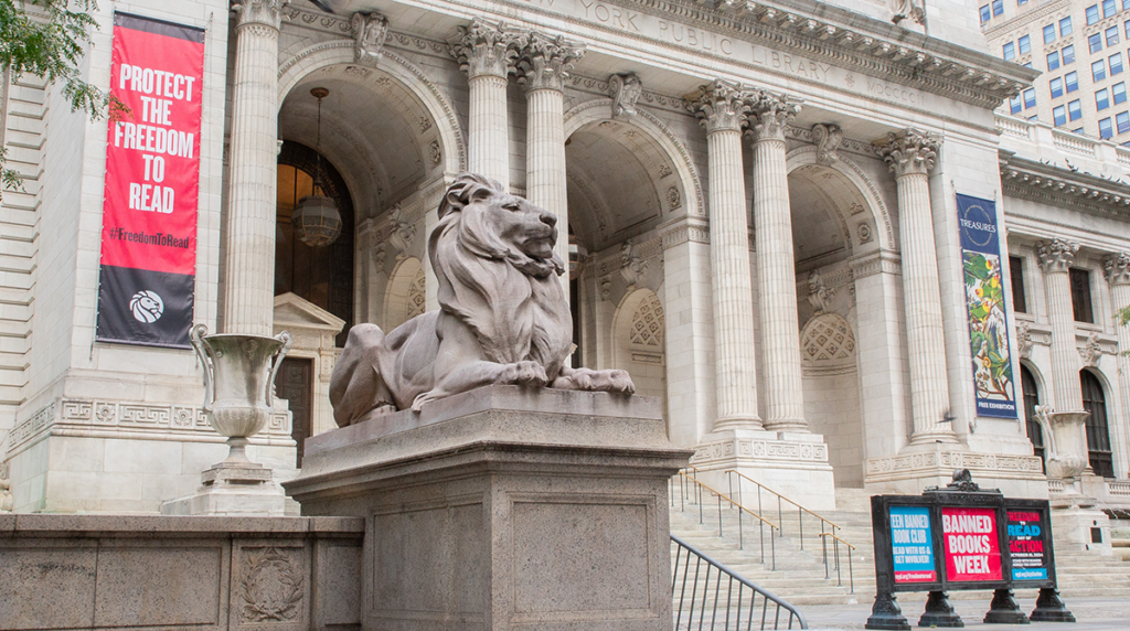 The New York Public Library’s flagship location, the Stephen A. Schwarzman Building, with "Protect the Freedom to Read" banner shown behind one of the lions that flank the entrance.